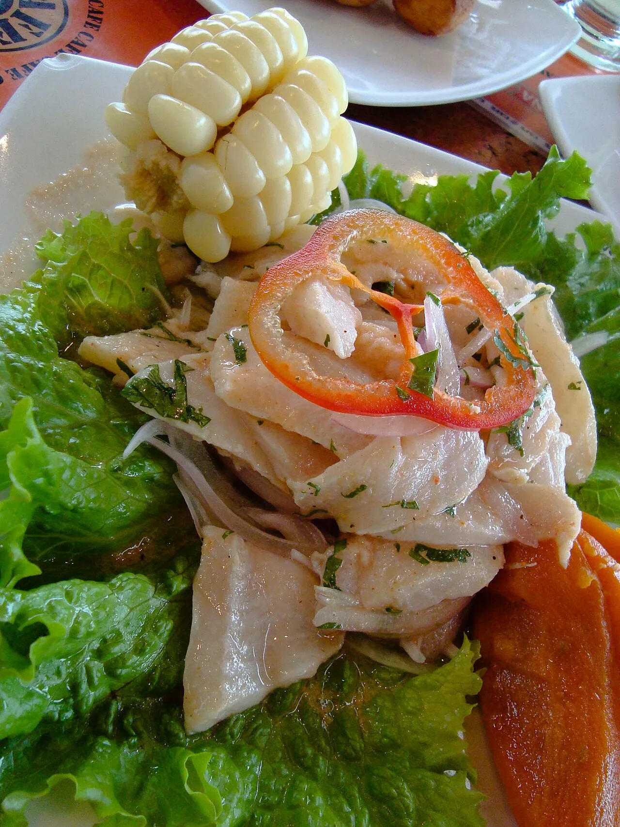 A plate of Peruvian ceviche with onion, chilli and corn